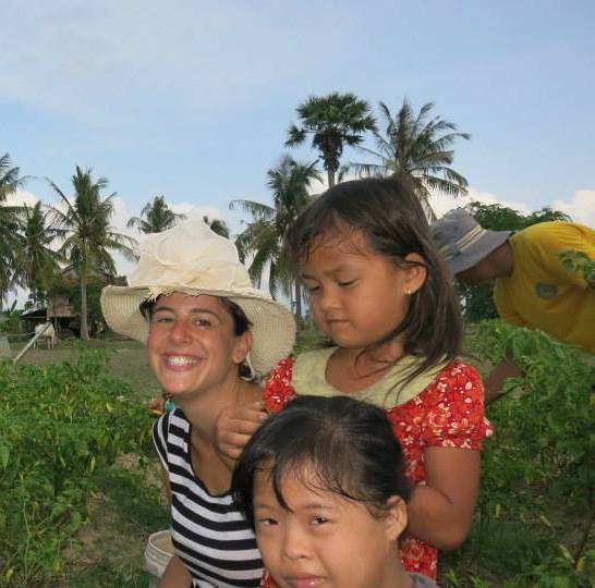 Women smiling next to two kids on a sunny farm field.